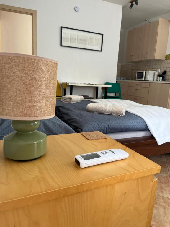 a table with a lamp and a remote control on it at Wash House Apartman in Győr