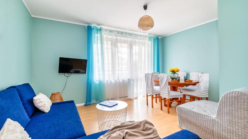 Sala de estar azul con sofá azul y mesa en Teleexpresu Apartamenty PIAMOLA en Krynica Morska