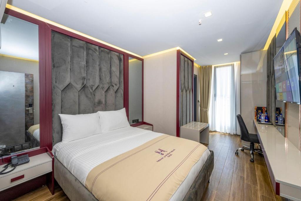 um quarto de hotel com uma cama grande e uma televisão em Heaven Premium Hotel İstanbul Airport em Arnavutköy