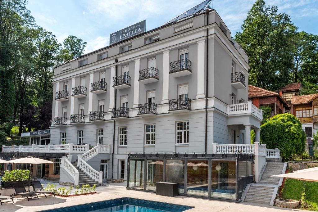 a hotel with a pool in front of it at Emilia Lux Rooms in Vrnjačka Banja