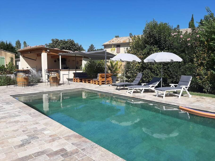 una piscina con sedie e ombrelloni accanto a una casa di Villa moderne dans la tranquillité de la campagne a Caderousse