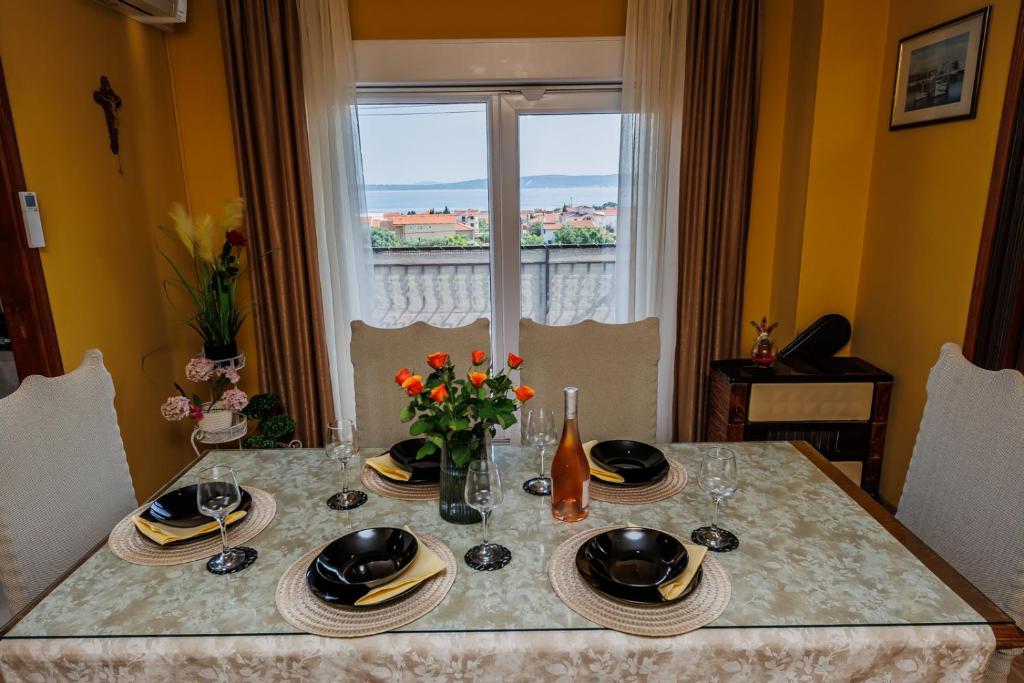 una mesa de comedor con platos y flores. en Luka, en Kaštela