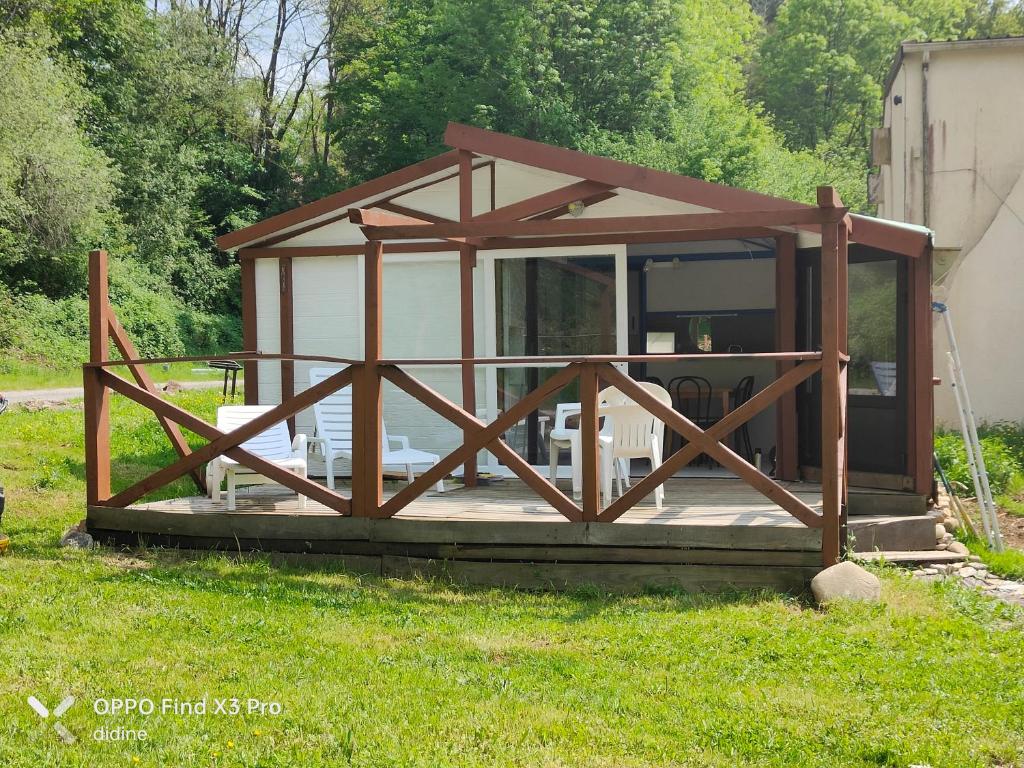 eine kleine Hütte mit einer abgeschirmten Veranda im Gras in der Unterkunft l'Espace in Latouille-Lentillac
