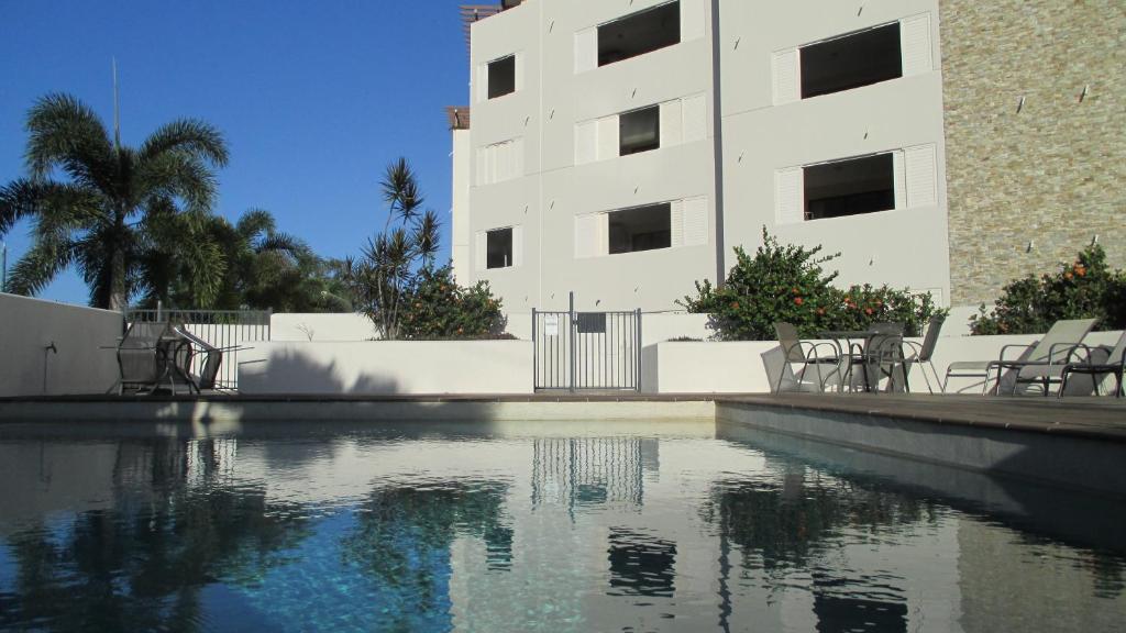 a large white swimming pool in front of a large building at Edge Apartments Cairns in Cairns