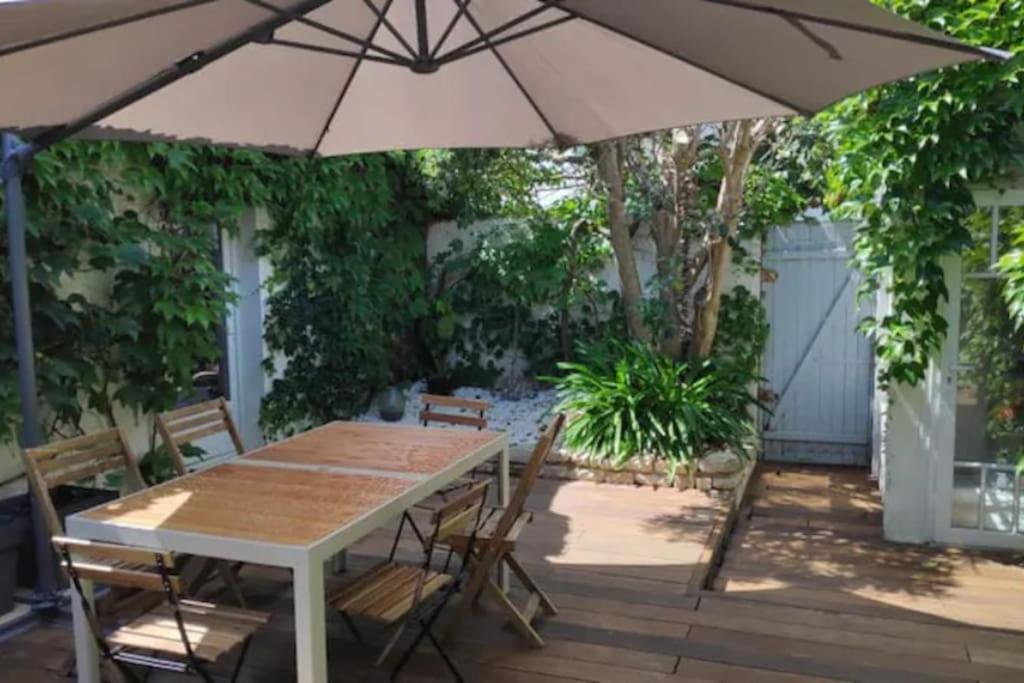 une table et des chaises avec un parasol sur une terrasse dans l'établissement Maison calme avec terasse proche centre ville, à La Rochelle