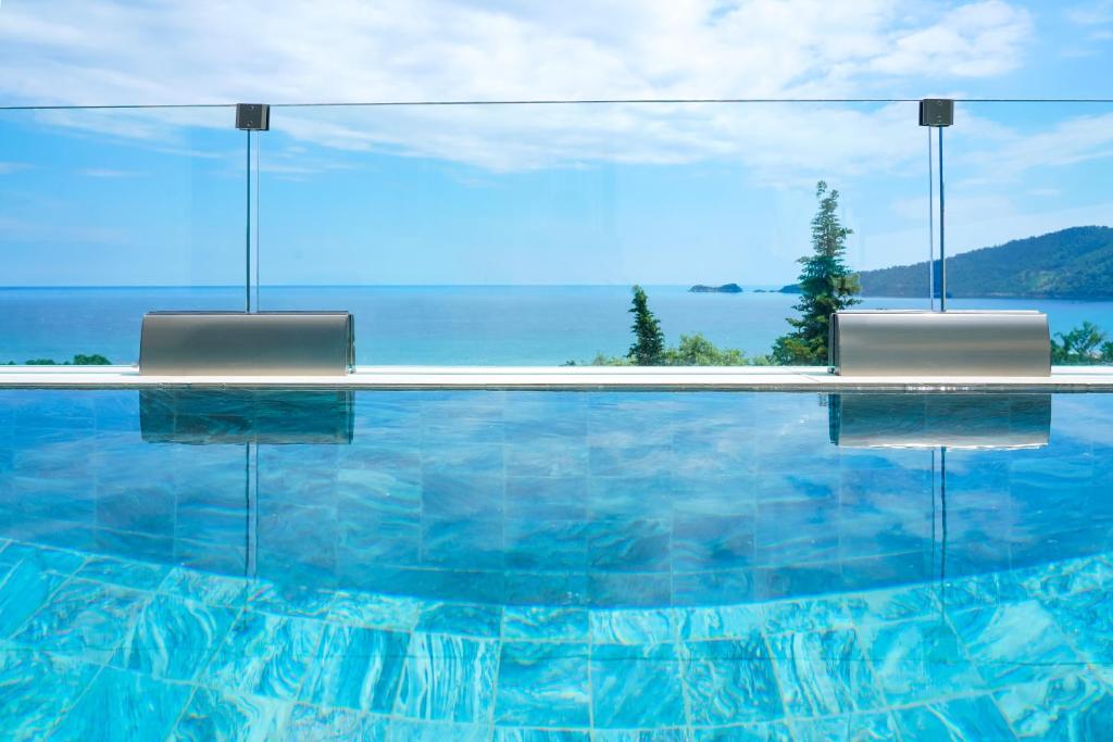 una piscina con due sedie e vista sull'oceano di Mythodea Prive Luxury Suites a Chrisi Ammoudia