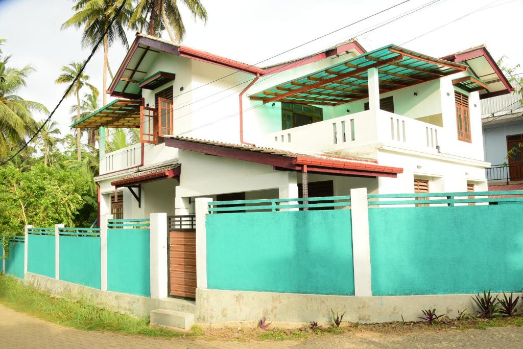a house with a blue fence in front of it at Sadisa Villa in Hikkaduwa