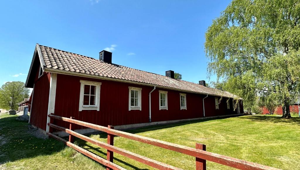 ein rotes Haus mit einem Zaun davor in der Unterkunft Valla Vandrarhem in Linköping