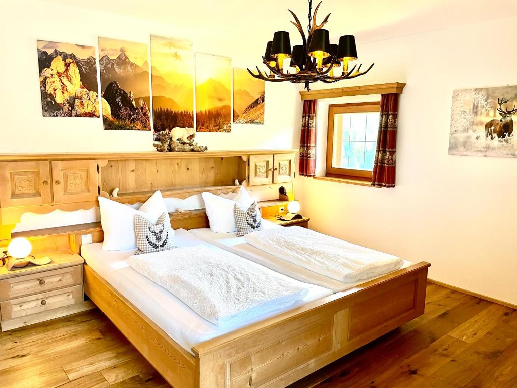 ein Schlafzimmer mit einem großen Bett und einem Kronleuchter in der Unterkunft Chalet Bernardi Apartments in St. Ulrich in Gröden