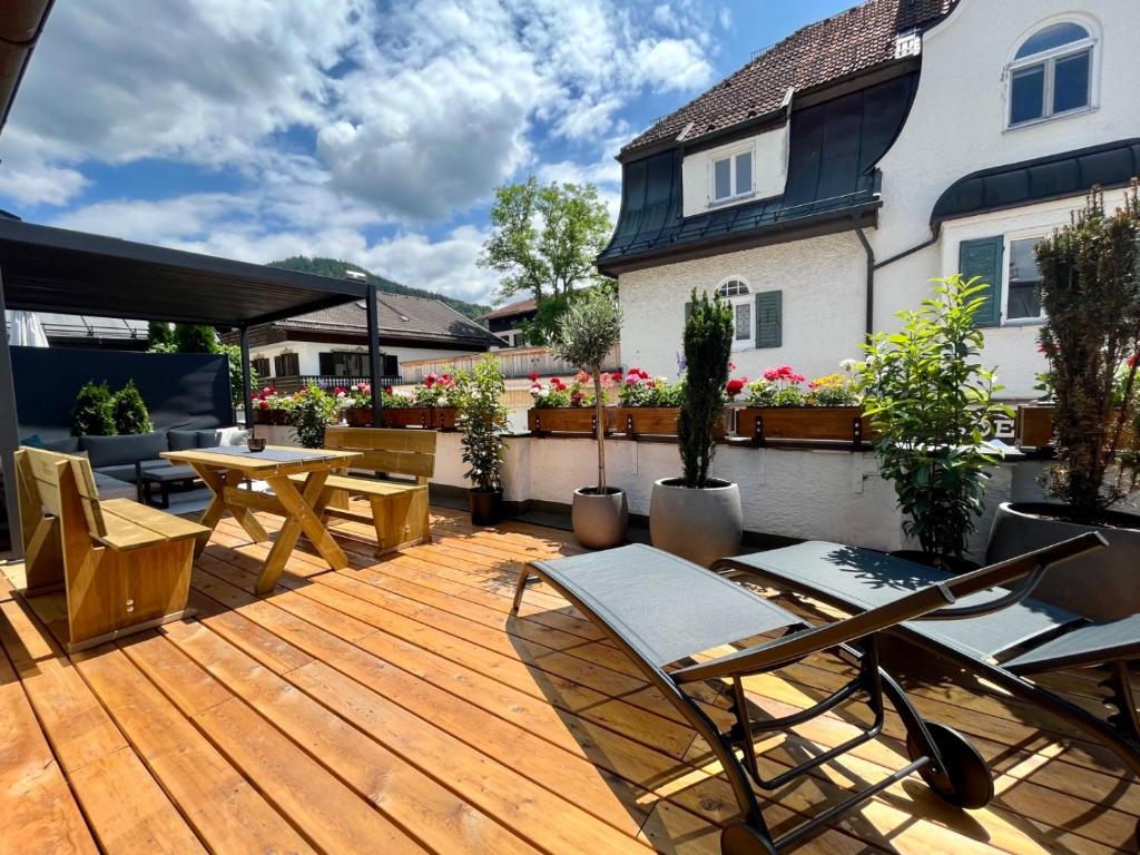 una terraza de madera con sillas y mesas en una casa en FeWo Rosenstraße - Exklusive Ferienwohnung im Herzen von Tegernsee en Tegernsee