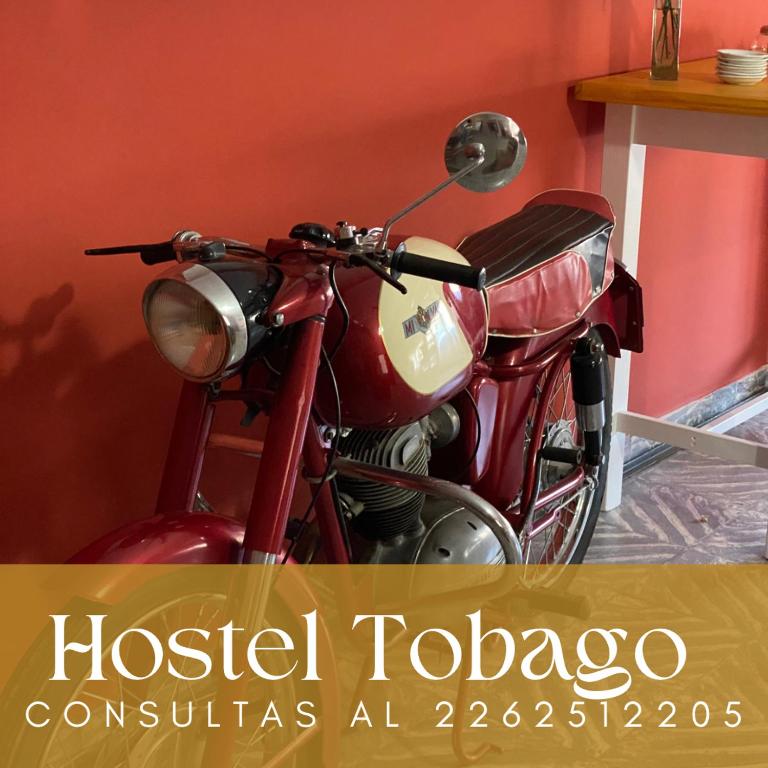 a red motorcycle parked next to a red wall at Hosteria Tobago in Necochea