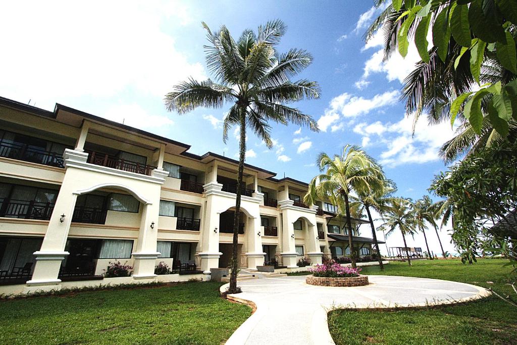 un edificio con una palmera delante de él en Khaolak Orchid Beach Resort - SHA Extra Plus en Khao Lak