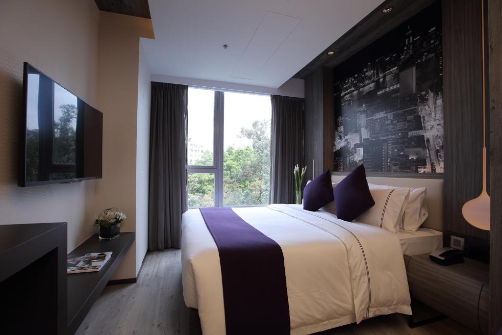 a hotel room with a large bed and a window at The Perkin Hotel in Hong Kong