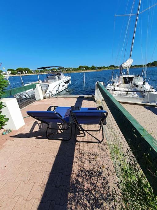 une table et un banc sur un quai avec un bateau dans l'établissement Marina La Plagette RDC appontement XL parking, au Grau-du-Roi