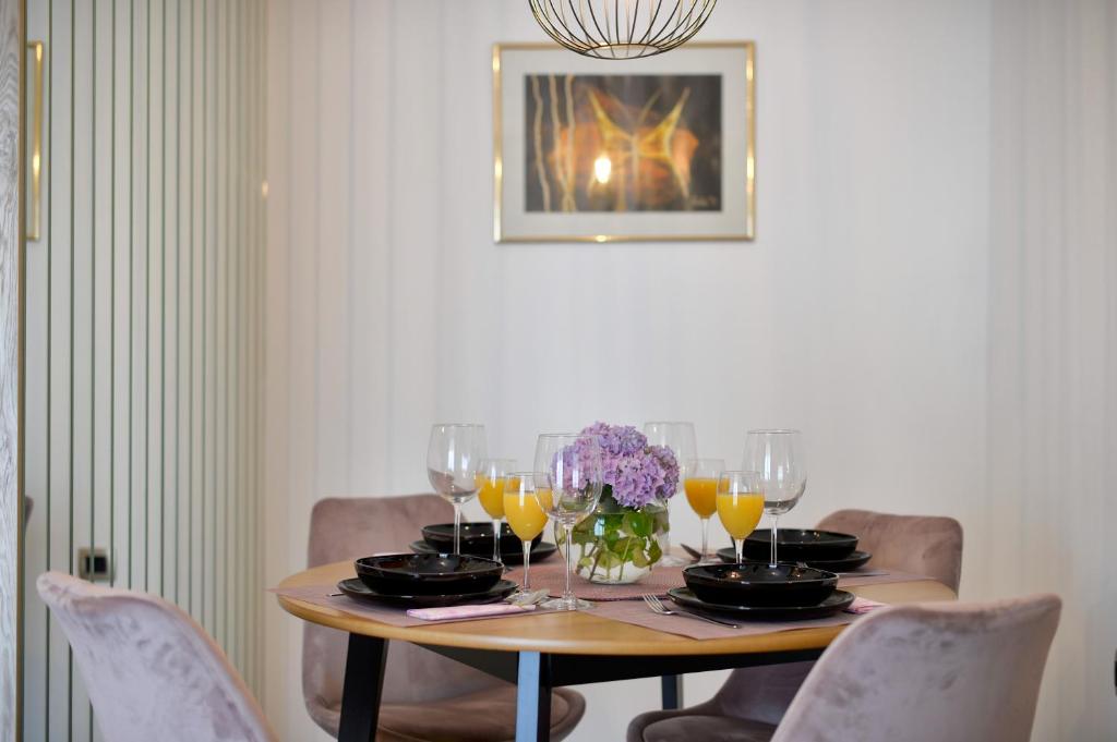 Tonka studio apartman في Križevci: طاولة غرفة الطعام مع كؤوس النبيذ والزهور عليها