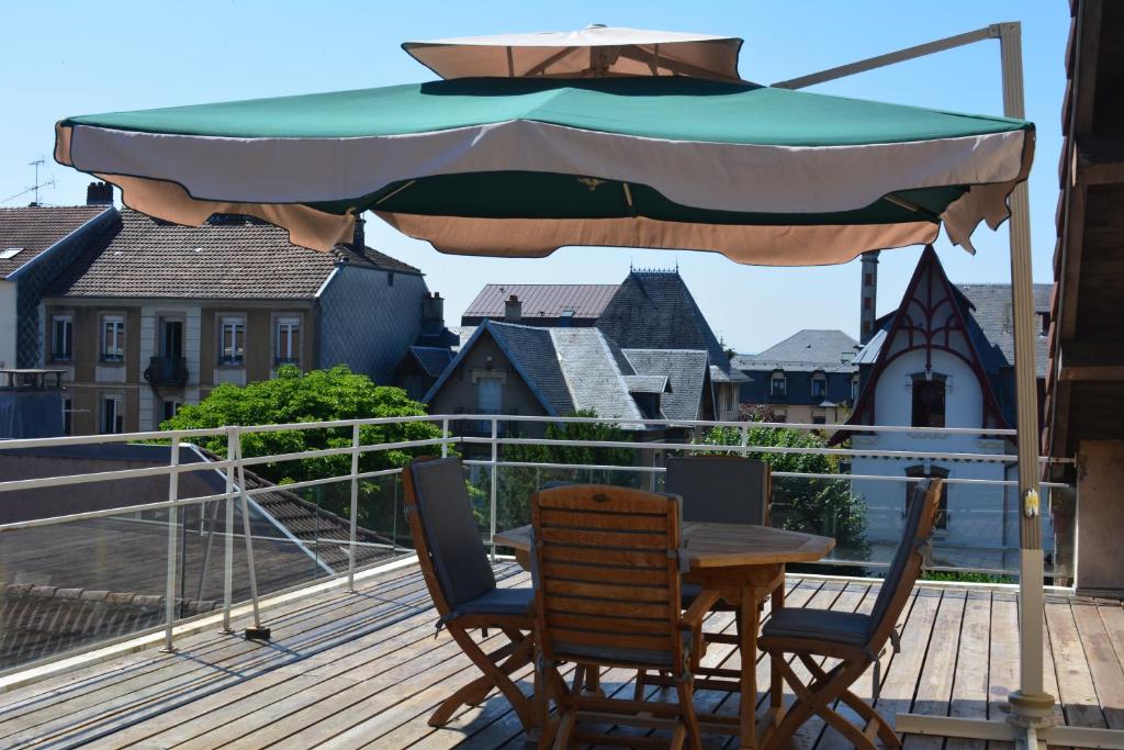 a table and chairs under an umbrella on a deck at Appartement-terrasse parking privé Meublé de Tourisme 4 étoiles in Belfort