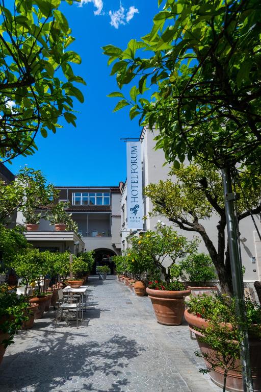 a building with plants and tables and chairs and trees at Hotel Forum in Pompei