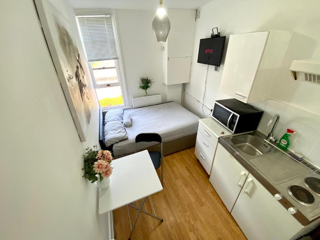 a small apartment with a bed and a sink at Private Studio Flat close to Central London with Smart TV and workspace in London