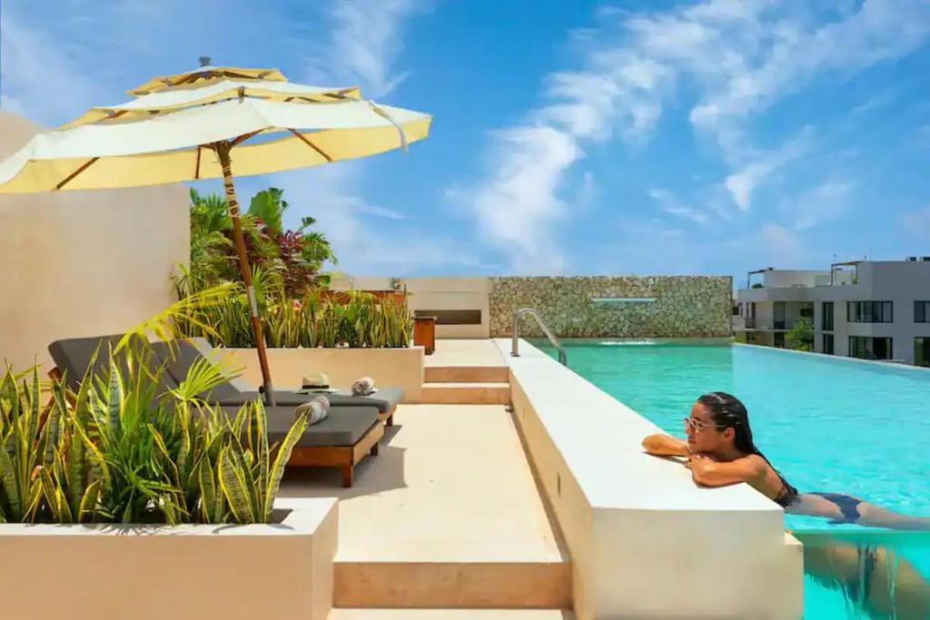a woman laying in the swimming pool at a hotel at Ave Del Paraíso PH - 3-Bedrooms and a Pool in Tulum
