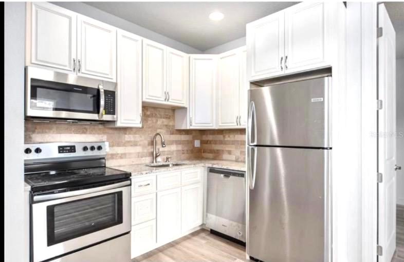 cocina con armarios blancos y nevera de acero inoxidable en NEW LISTING Sarasota Pet-friendly 1 Bedroom Apartment, en Sarasota