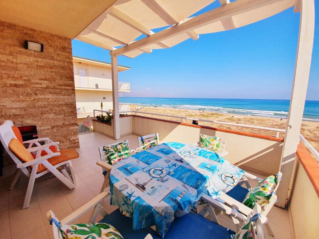 uma varanda com uma mesa e cadeiras e o oceano em Castellammare Holiday em Alcamo Marina
