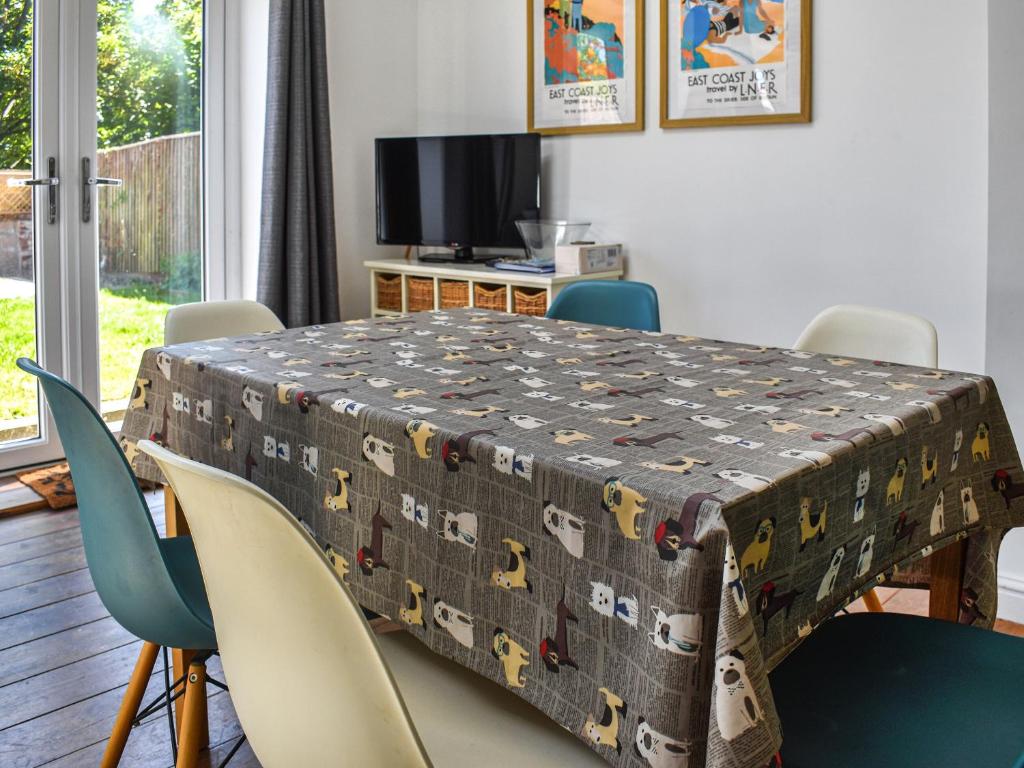 une table à manger avec des chaises et un tissu de table dans l'établissement Flint House, à Sheringham