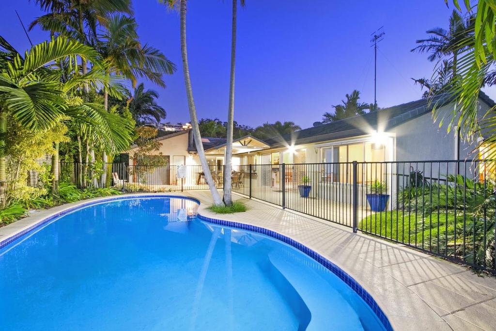 a swimming pool in front of a house with palm trees at 26 Witta Circle, Noosa Heads in Noosa Heads