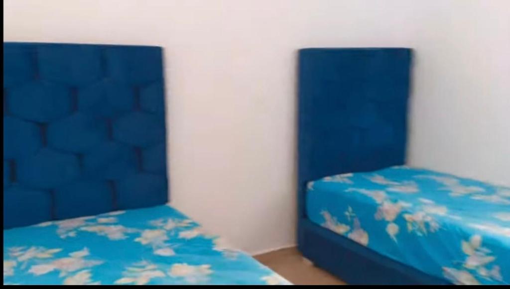 2 posti letto in una camera con lenzuola blu e fiori di Appartement 2 chambres résidence Sables d’or Tanger a Tangeri