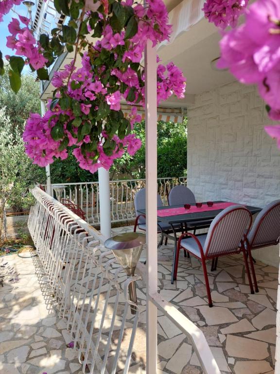 un tavolo e sedie su un patio con fiori rosa di Apartment Emili Marina a Marina