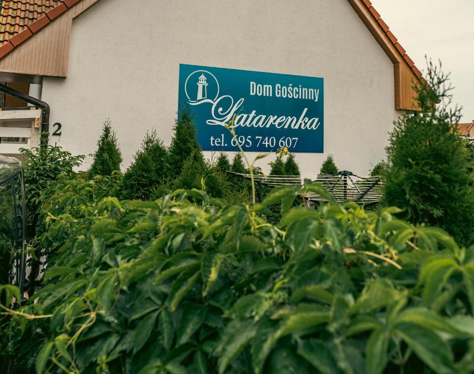 een bord voor een tuin voor een gebouw bij Dom Gościnny Latarenka in Niechorze