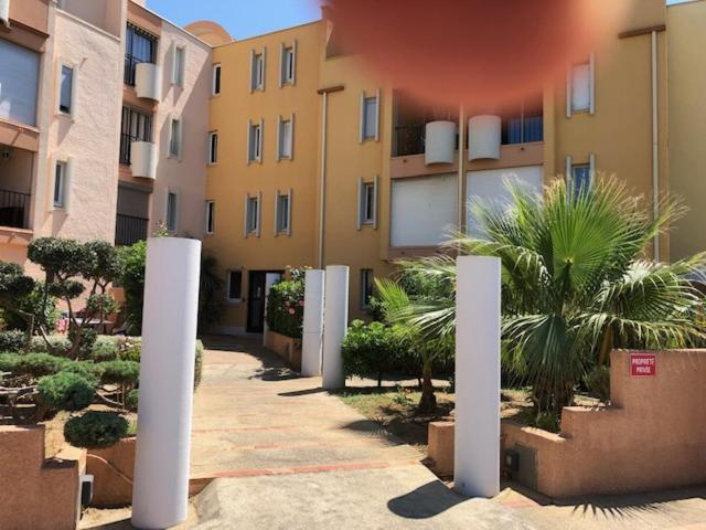 szereg budynków z palmami na dziedzińcu w obiekcie Gruissan (Aude) Appartement calme, vue sur port de plaisance -Clim, Empl.Parking w mieście Gruissan