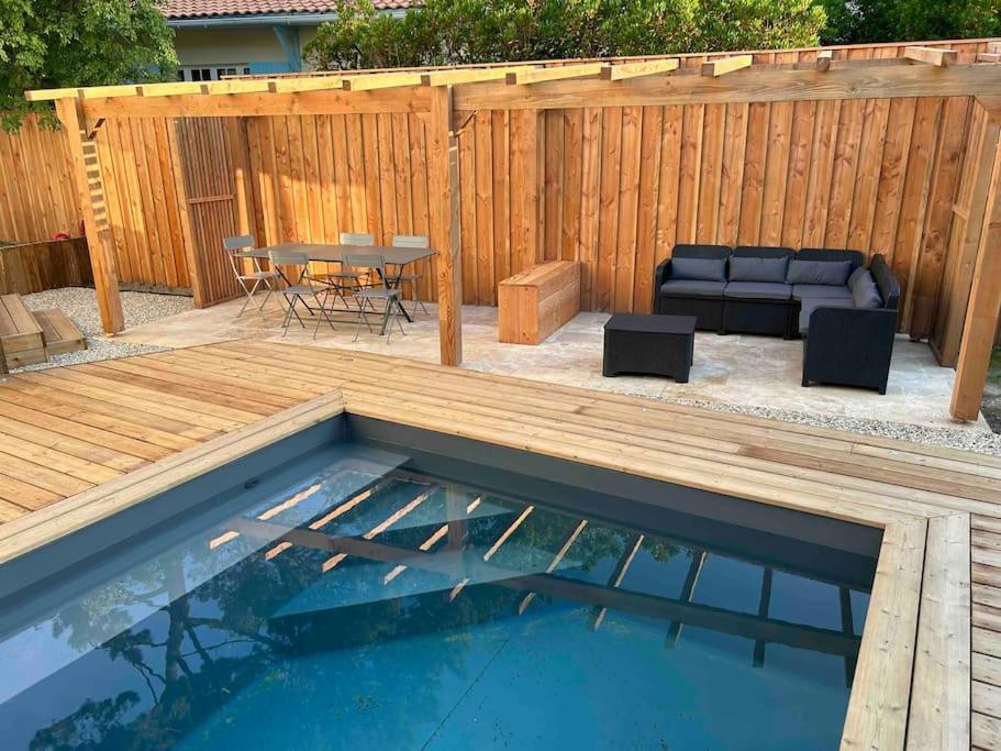 a patio with a pool and a table and a couch at Charmante maison aux Abatilles-piscine-8 pers in Arcachon