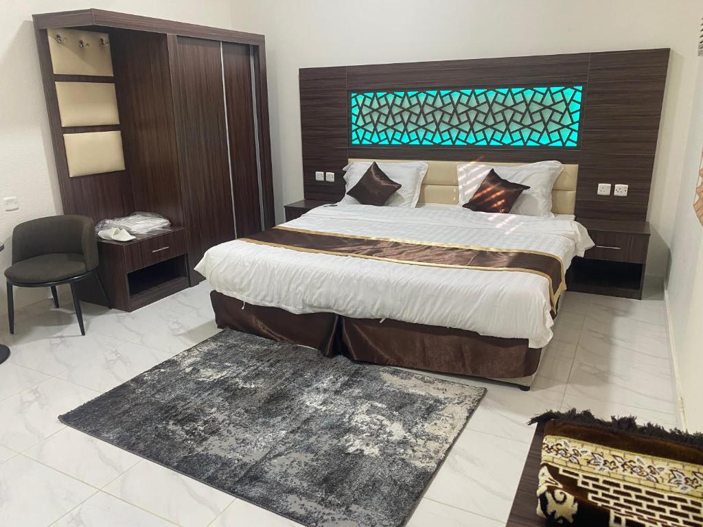 um quarto com uma cama grande e uma cadeira em Wind alula em Al Ula