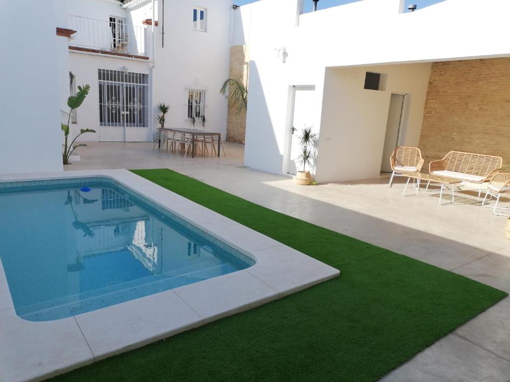 a house with a swimming pool and a green lawn at La casa de los marqueses in Villanueva del Ariscal