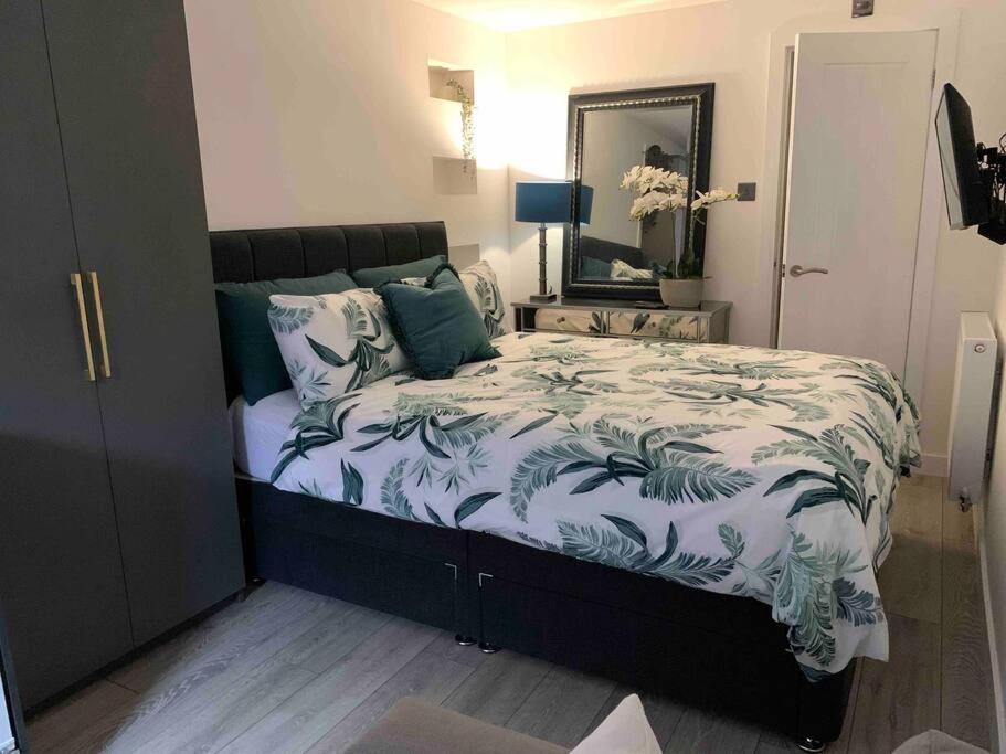 1 dormitorio con 1 cama con edredón verde y blanco en Private entrance 1 bed studio near Salford Royal, en Mánchester