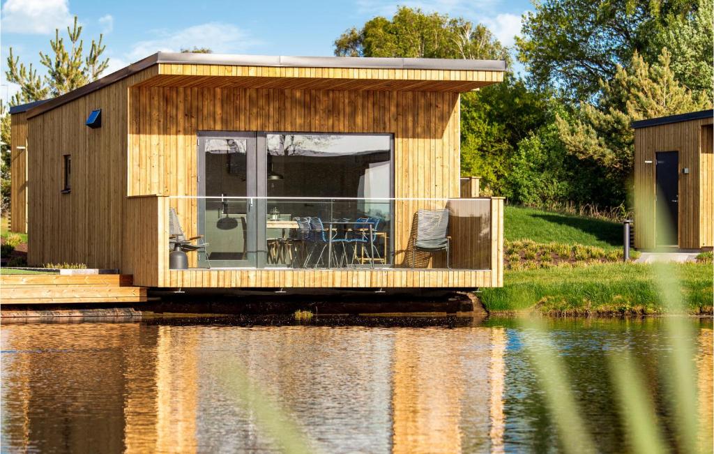 una pequeña casa de madera en el agua junto a un lago en Amazing Home In Strandlida With Sauna, Wifi And 2 Bedrooms, en Strandlida