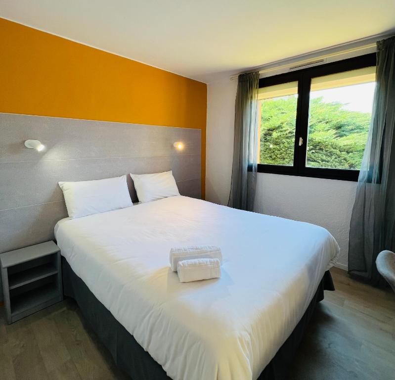 een slaapkamer met een groot wit bed en een raam bij Hôtel Le Forestia in Pannes