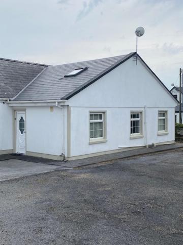 ein weißes Haus mit einem Dach in der Unterkunft JMD Lodge - Self Catering Property in the heart of The Burren between Ballyvaughan, Lisdoonvarna, Doolin and Kilfenora in County Clare Ireland in Ballyvaughan