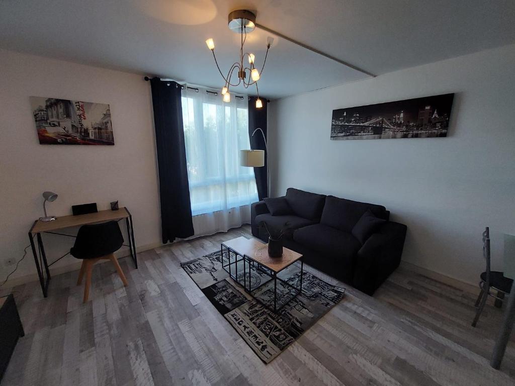 a living room with a couch and a table at Appartement équipé proche aéroport et gare in Beauvais