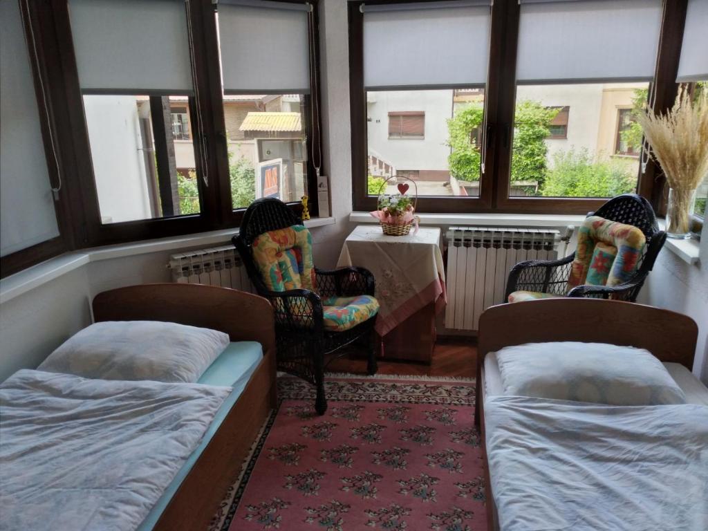 a room with two beds and a table and windows at Sobe Centar in Visoko