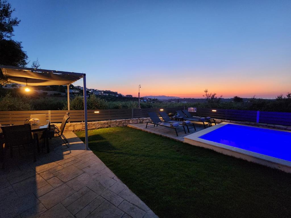 a backyard with a swimming pool at dusk at Villa Dionisia with private pool in Roumelí