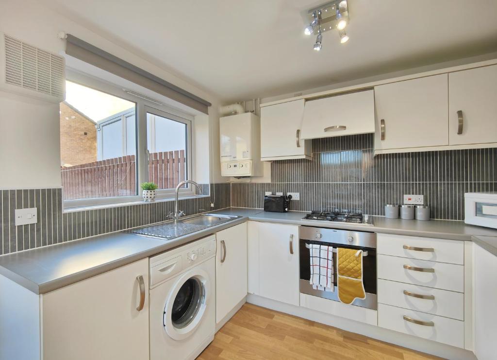 a kitchen with white cabinets and a washer and dryer at The Metcombe - Bright Townhouse 5 Minutes To Manchester City Centre With Free Parking in Manchester