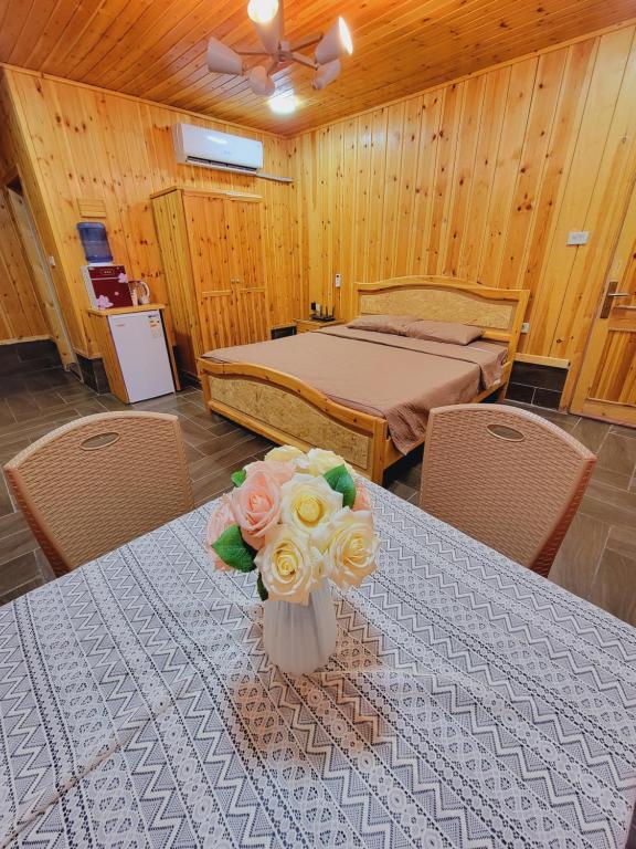 Un dormitorio con una cama y una mesa con flores. en atoom lodge, en Jerash