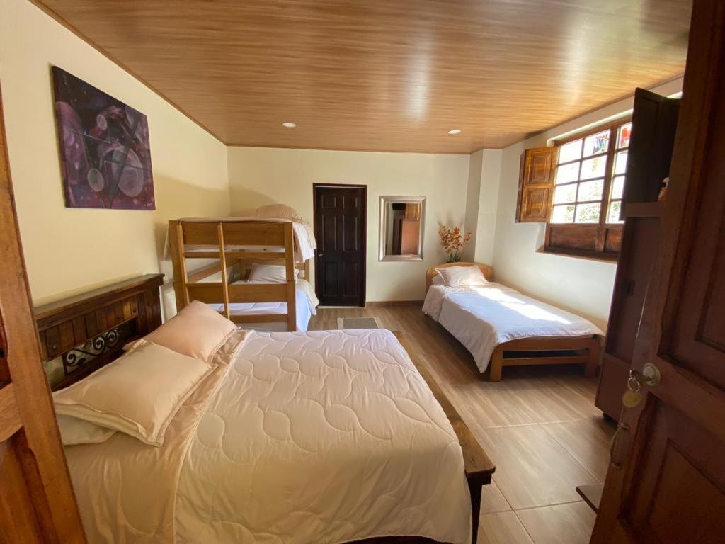 a bedroom with two beds and a window at Hotel Villa Mercedes Colonial in Sopó