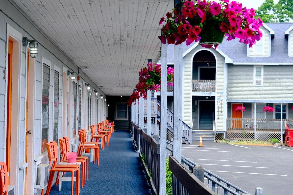 una fila de sillas sentadas en un porche con flores en Dock House Inn, en Old Orchard Beach