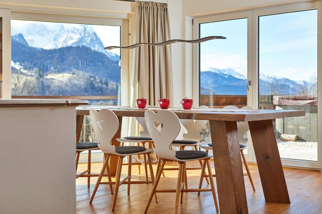 a dining room table and chairs with a view of mountains at Das Gsteig in Garmisch-Partenkirchen