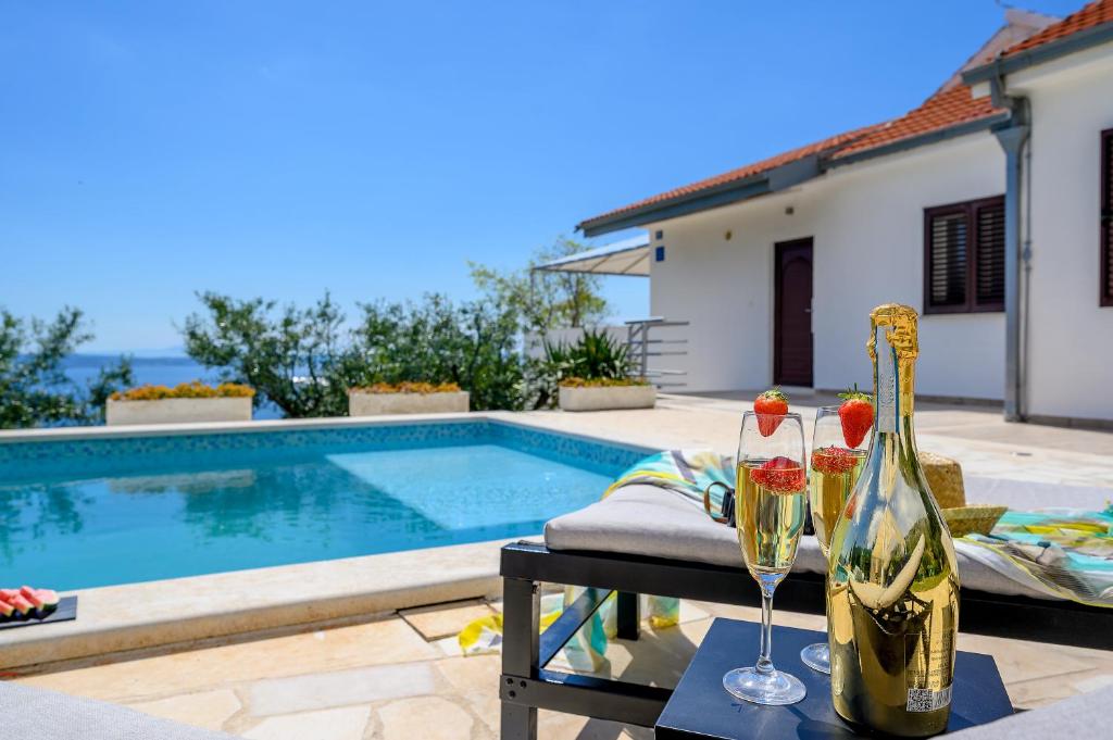 a villa with a swimming pool and two glasses of wine at Nudist friendly villa with fence arround pool and garden to relax and enjoy in Podstrana