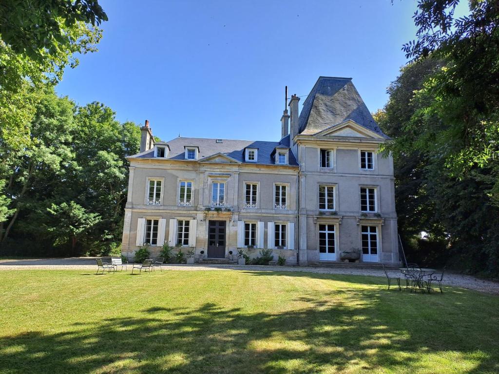 una grande casa bianca con un grande prato di La Maison Pelloquin a Bernières-sur-Mer
