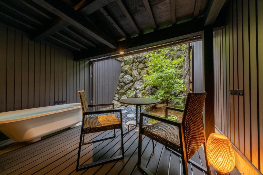 einen Balkon mit einer Badewanne, 2 Stühlen und einem Tisch in der Unterkunft Tsuki-Akari Takayama - Japanese modern Vacation Stay with an open-air bath in Takayama