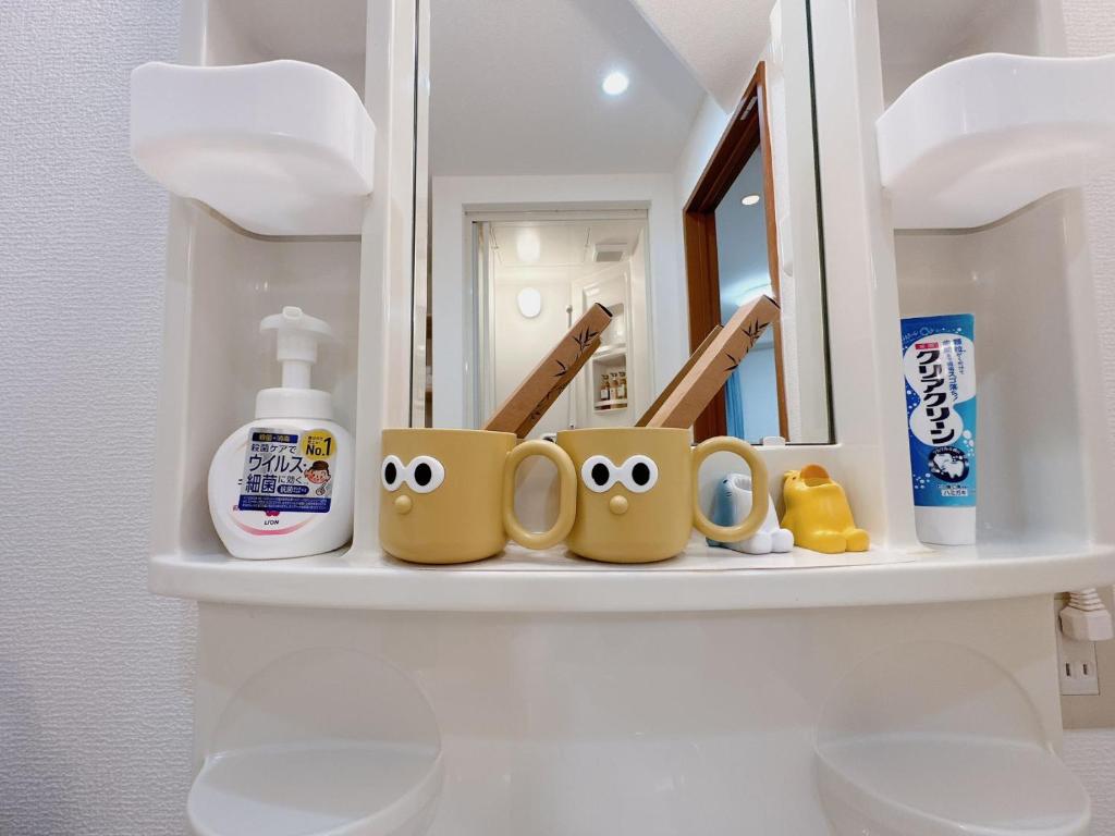 a shelf with mugs with faces on it in a bathroom at 三米-黒門市場-黑门市场-kuromon 202タイプ in Osaka